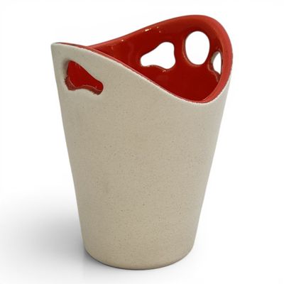 a red and white vase with a hole in it
