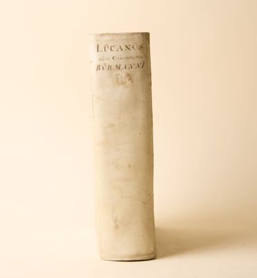 un vieux livre posé sur une table à côté d'un mur blanc