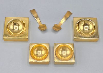 four pieces of gold colored metal on a white surface