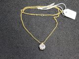 a close up of a gold necklace with a diamond on it