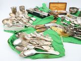 a lot of silverware on a table with a green cloth