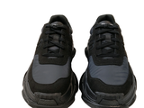 a pair of black sneakers that are on a white surface