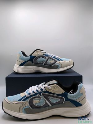 une paire de baskets bleues et grises posée sur une boîte