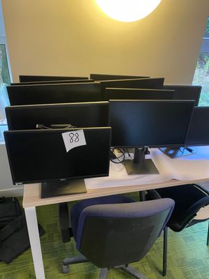 four computer screens on a desk in a room