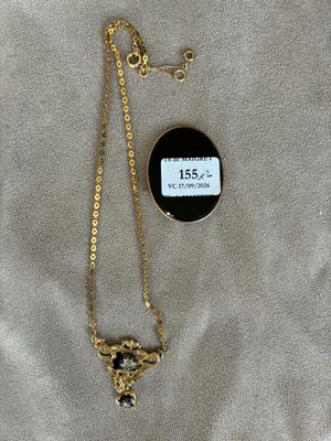 un collier en or avec un pendentif noir et blanc et une chaîne en or