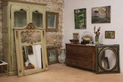une commode et un miroir dans une pièce où sont accrochés des tableaux au mur