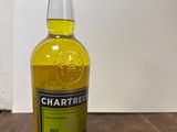 une photo d'une bouteille de liqueur de citron Chartreuse posée sur une table en bois