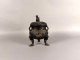 a small bronze incense pot with a man on top of it