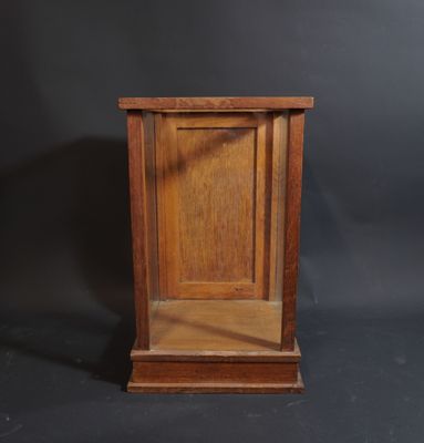 une vieille horloge en bois posée sur un socle, sur fond noir