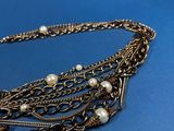 a close up of a necklace with pearls on a blue background