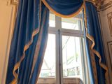 a blue curtain with gold trim and a mirror in a room