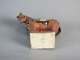 porcelain figurine of a dog with a box on a gray surface