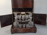 bottles and glasses in a wooden case sitting on top of a table