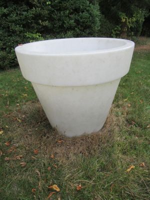 une grande jardinière blanche posée au milieu de la pelouse
