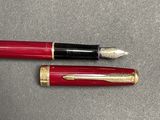 a red pen and a black pen sitting next to each other