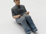 a figurine of a man sitting on a white surface