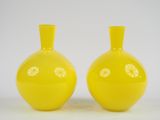 une paire de vases jaunes posés sur une surface blanche, sur fond blanc