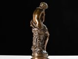 a bronze statue of a man sitting on top of a white table