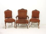 three antique chairs are lined up against a white wall