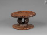 an old wooden table with a circular base and a wooden top