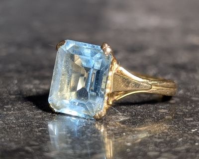 une bague sertie d'une topaze bleue, posée sur une table