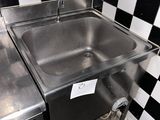 un évier en acier inoxydable dans le coin d'un mur à carreaux noirs et blancs
