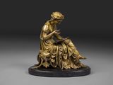 une statue en bronze représentant une femme assise sur un rocher
