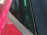 a dog sitting in the back seat of a red car