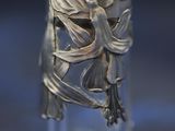 a close up of a silver vase with a bird on it