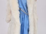 poupée vêtue d'une robe bleue et d'un manteau de fourrure, debout sur une surface blanche