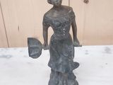 une statue représentant une femme tenant un éventail, posée sur une table