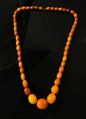 a close up of a necklace with orange beads on a black surface