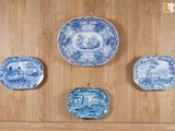 Quatre assiettes bleues et blanches sont accrochées à un mur en bois.