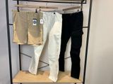 deux paires de pantalons suspendues à un portant dans un magasin de vêtements