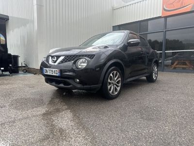 the black nissan juke is parked in front of a building