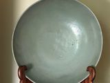 a green bowl sitting on top of a wooden stand