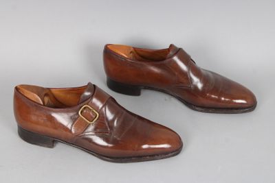 une paire de chaussures en cuir marron avec des boucles sur un fond blanc