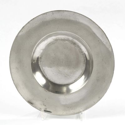 a silver plate on a stand on a white surface