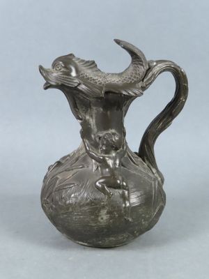 a silver vase with a fish on it on a table