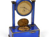 une petite horloge bleue sur laquelle est posée une pièce de monnaie