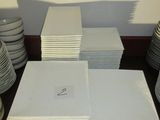 plusieurs piles d'assiettes et de tasses blanches posées sur une table, avec un mur en arrière-plan