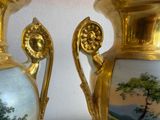 two gold vases with paintings on them sitting on a table