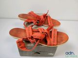 une photo d'une paire de sandales orange ornées d'un ruban noué autour