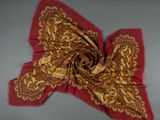 a close up of a red and gold scarf on a gray surface