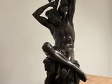 statue of a man holding a sword on a pedestal in a room