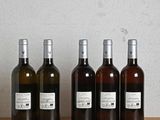 several bottles of wine are lined up on a wooden table