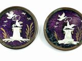 paire de boutons violets et blancs représentant un oiseau perché sur une souche d'arbre