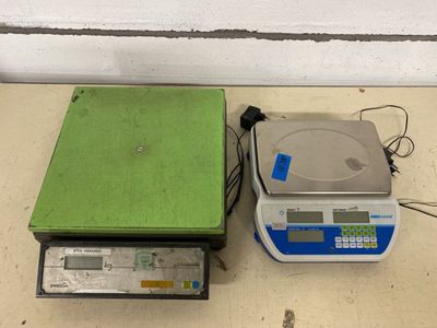 une balance recouverte d'un couvercle vert, à côté d'une autre balance recouverte d'un couvercle vert