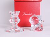 two glass candlesticks sitting next to a red box