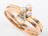 a close up of a gold ring with two pearls and a diamond